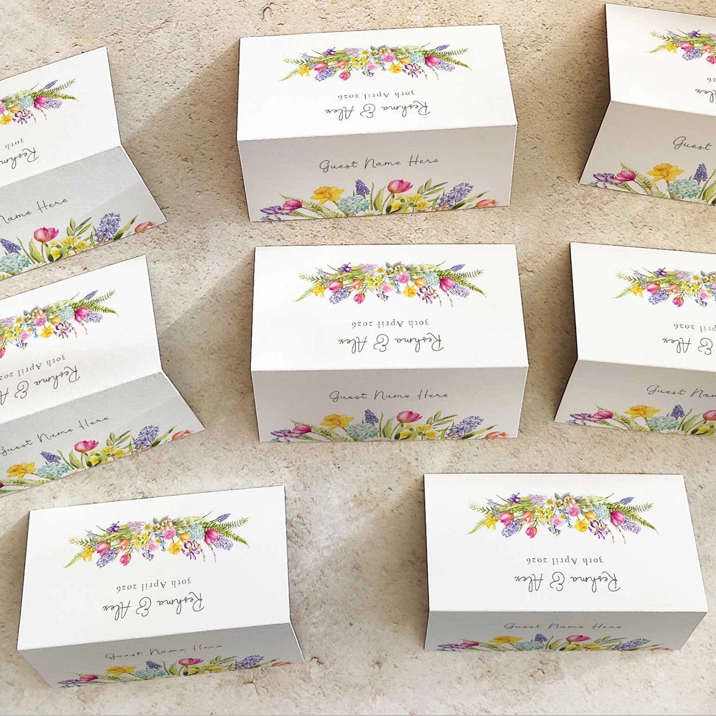 Set of white place cards with floral designs and text on a beige surface