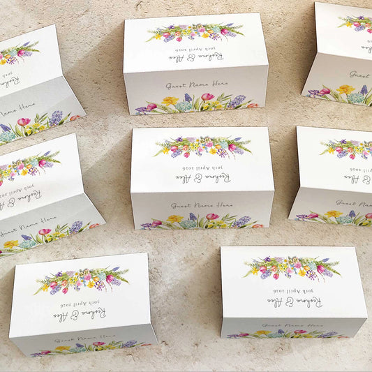 Set of white place cards with floral designs and text on a beige surface