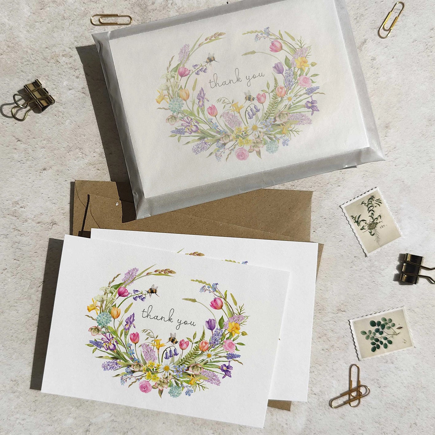 Two 'thank you' cards with spring themed floral designs on a textured surface.