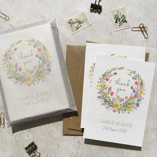 Set of personalized 'thank you' cards with floral designs on a textured surface.