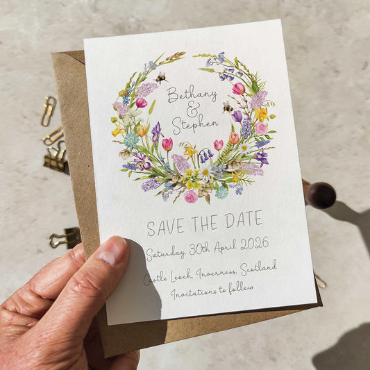 Save the date card with floral design held by a hand on a neutral background