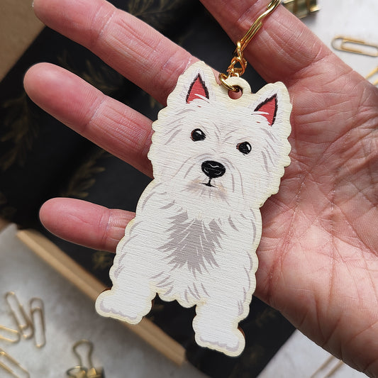 Hand holding a keychain with a dog design against a blurred background