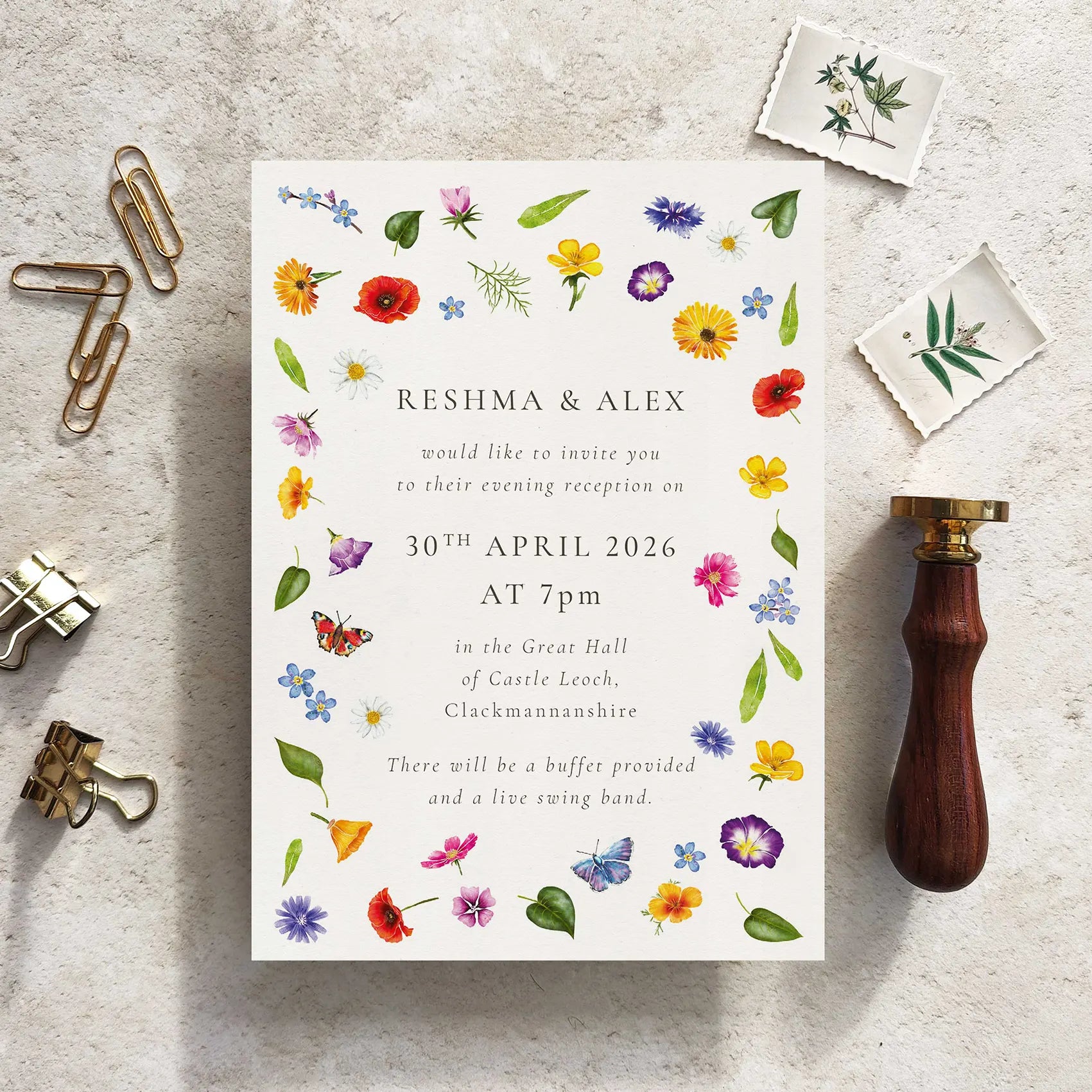 Wedding invitation card with floral design on a textured surface with stationery items.