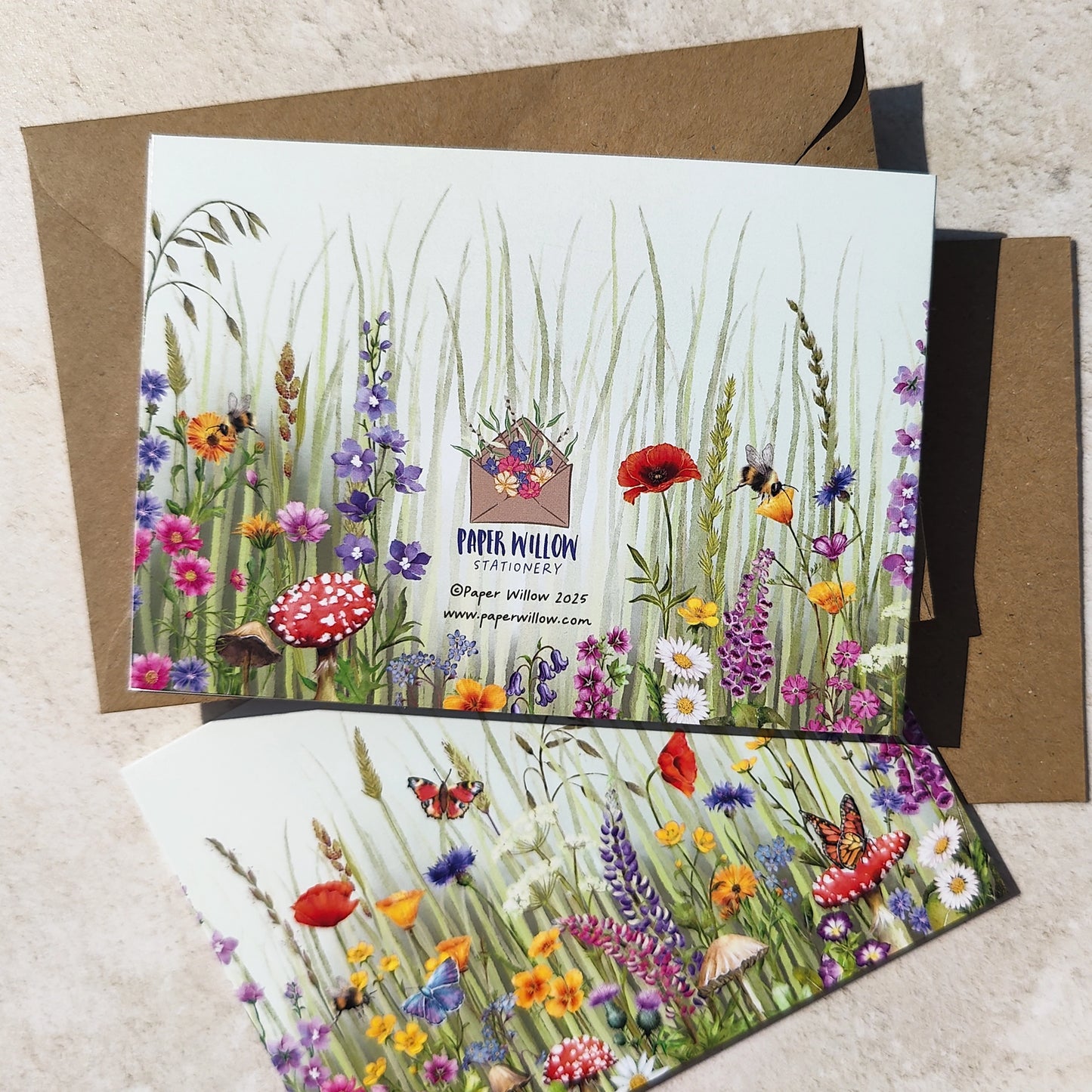 Greeting card with a colorful illustration of flowers, butterflies, and mushrooms on a textured surface.