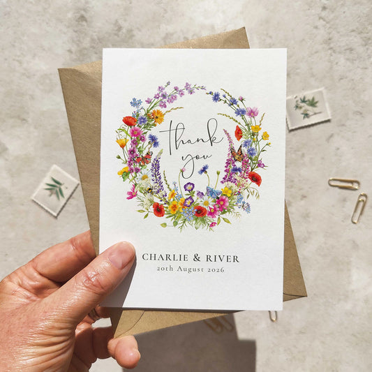 Greeting card with floral design and text held by a hand on a textured surface.